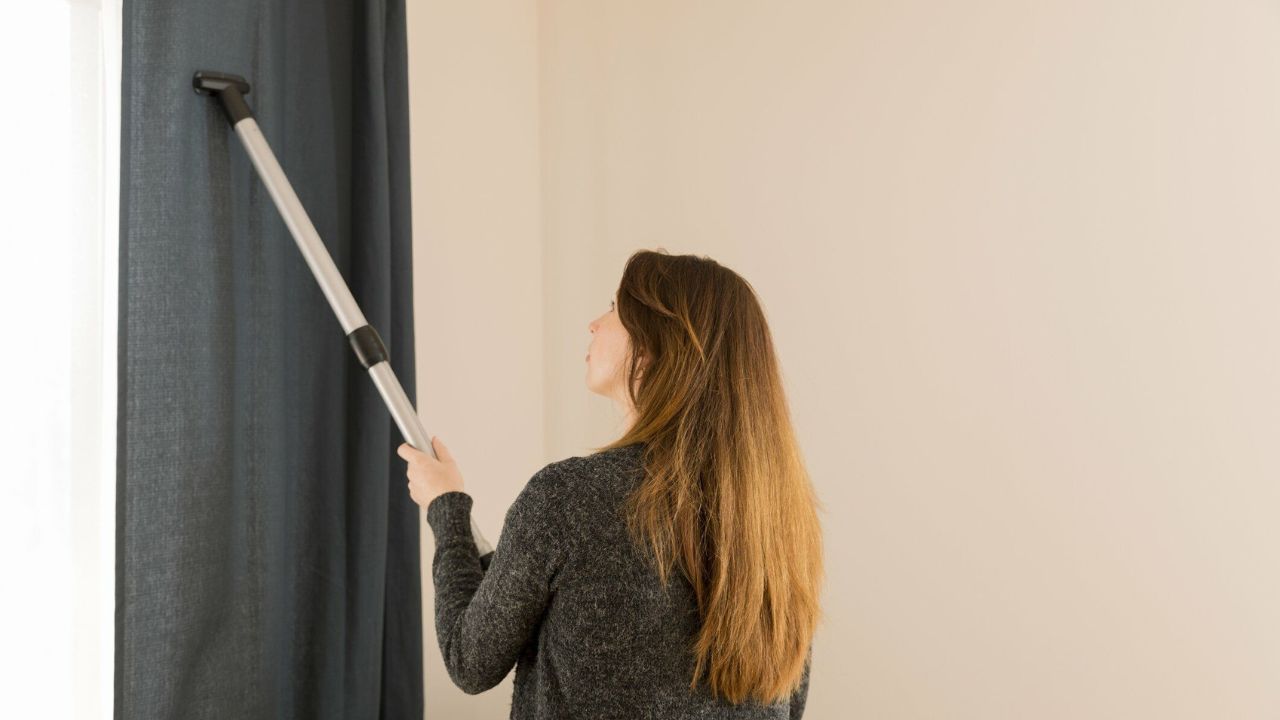 mulher passando aspirador em cortina
